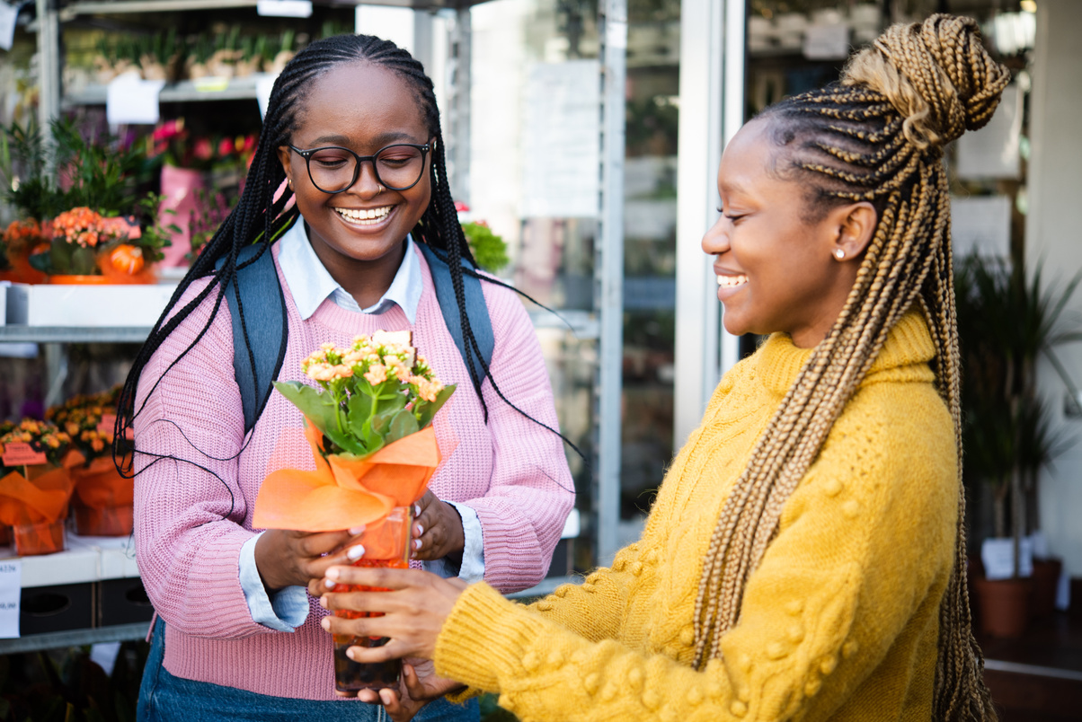 Two happy African girlfriends buying flowers